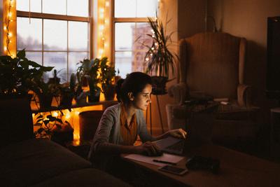 Woman using a voice assistant beside a lamp, showing best smart home starter kits for beginners in action.