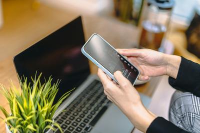 Close-up of hands editing an email on a smartphone in an office, showing Apple Intelligence on iPhone 17 features.